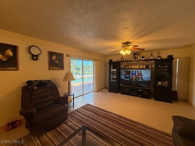 tiled living room featuring ceiling fan and a textured ceiling