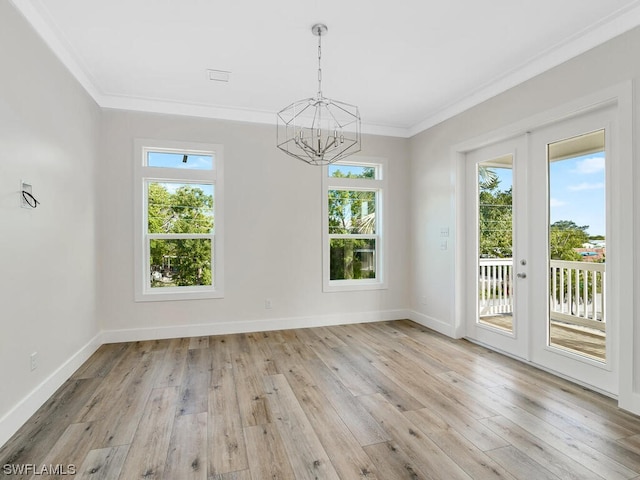 empty room featuring a notable chandelier, light wood-type flooring, and a wealth of natural light