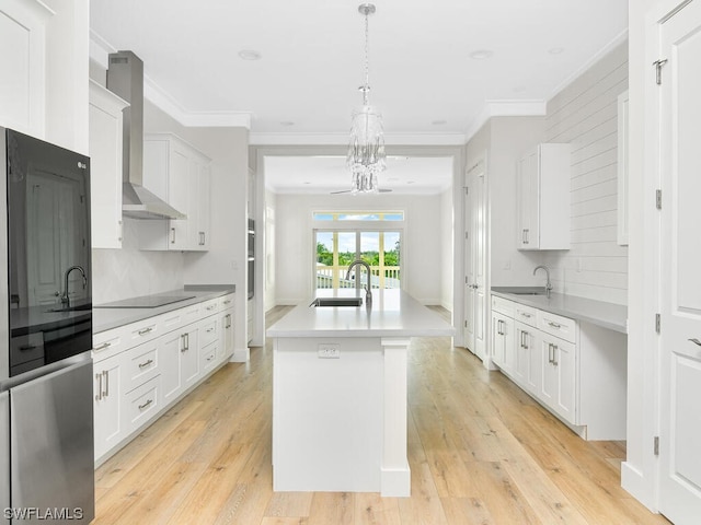 kitchen featuring an island with sink, white cabinets, sink, and light hardwood / wood-style flooring