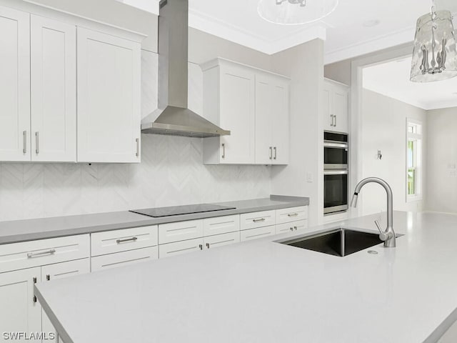 kitchen featuring wall chimney range hood, tasteful backsplash, black electric stovetop, white cabinets, and hanging light fixtures