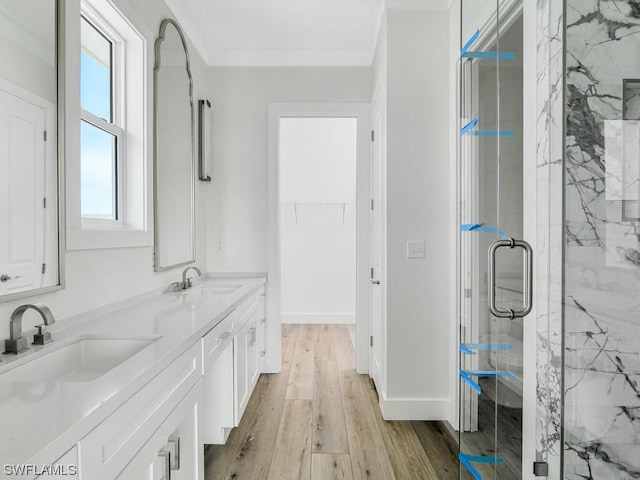 bathroom featuring double vanity, wood-type flooring, a shower with door, and ornamental molding