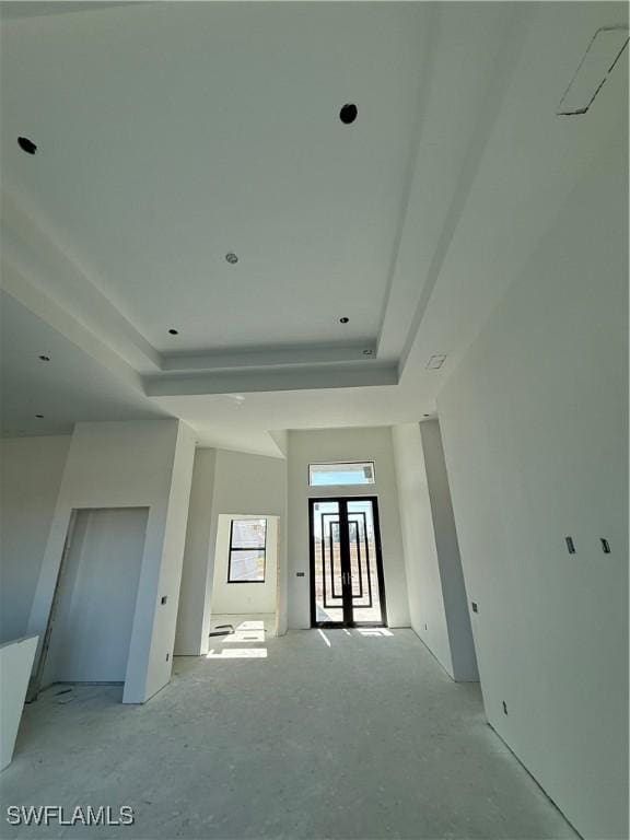 empty room with french doors and a raised ceiling