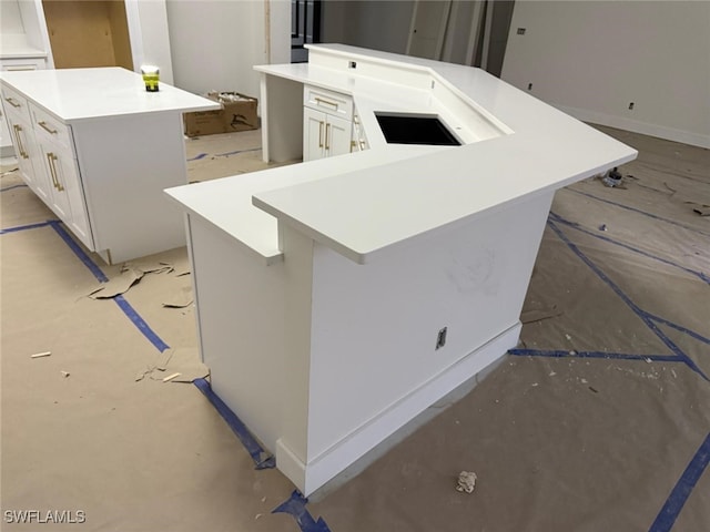 kitchen featuring a breakfast bar, white cabinets, and a center island with sink