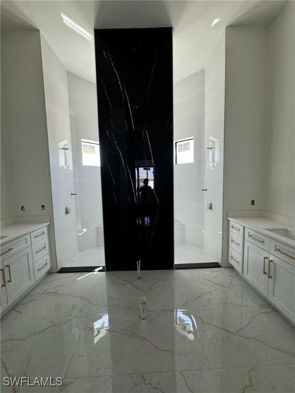 bathroom with vanity, marble finish floor, and walk in shower