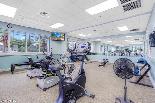 workout area featuring light carpet and a paneled ceiling