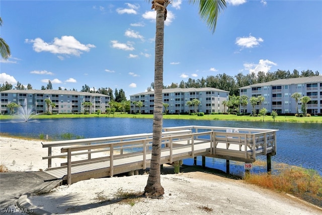 view of dock with a lawn and a water view