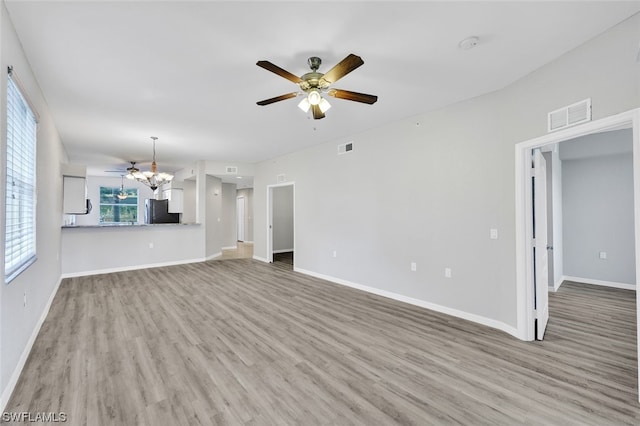 unfurnished living room with light hardwood / wood-style flooring and ceiling fan with notable chandelier