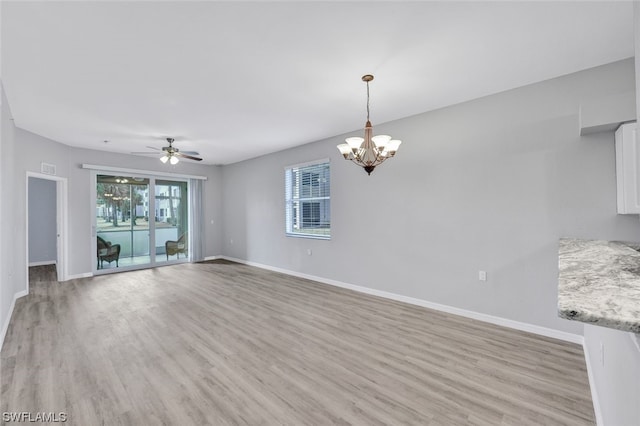 interior space with ceiling fan with notable chandelier and light hardwood / wood-style flooring