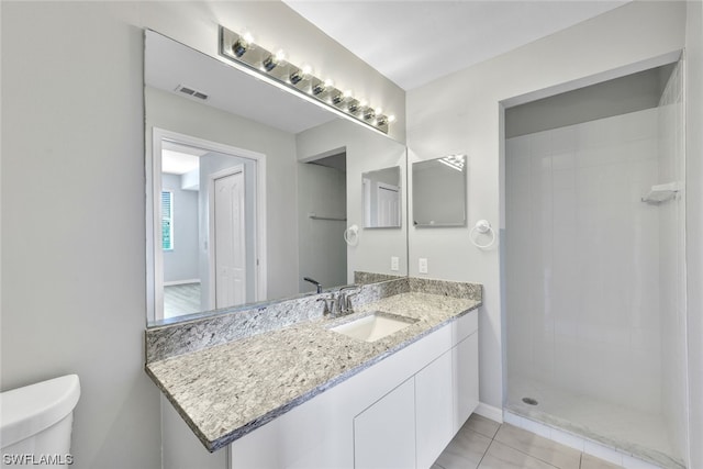 bathroom with toilet, a tile shower, vanity, and tile flooring