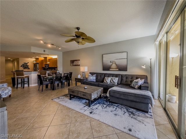 living room with a textured ceiling, ceiling fan, light tile floors, and track lighting