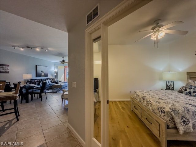 bedroom featuring light tile floors, rail lighting, and ceiling fan