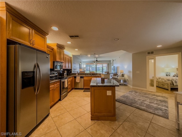 kitchen with ceiling fan, appliances with stainless steel finishes, light tile floors, and a center island