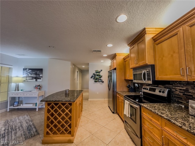 kitchen with light tile floors, dark stone counters, backsplash, and stainless steel appliances