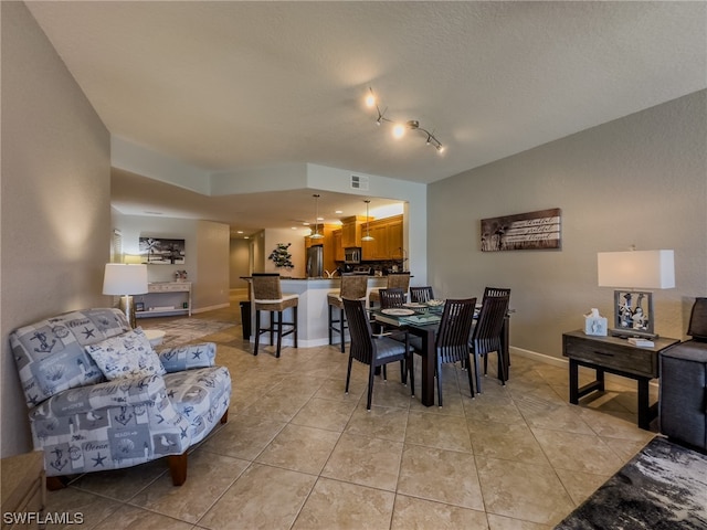 dining room featuring light tile flooring, a textured ceiling, and track lighting