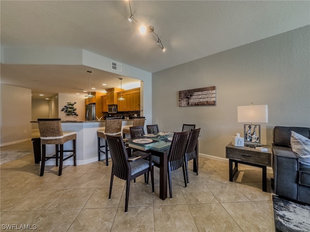 dining room featuring light tile flooring, a textured ceiling, and track lighting