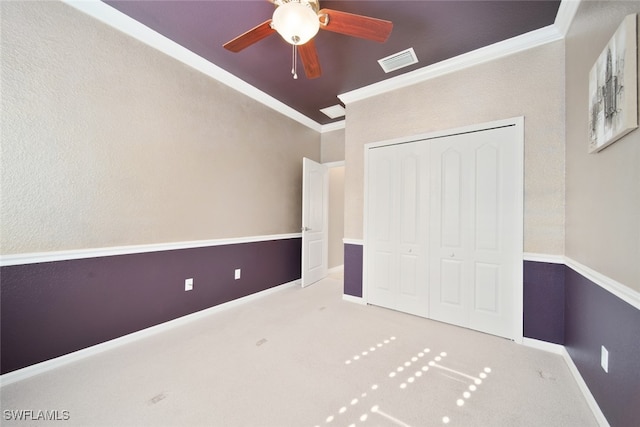 unfurnished bedroom featuring ceiling fan, ornamental molding, light carpet, and a closet