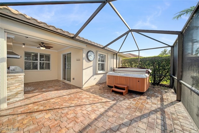 view of patio with area for grilling, ceiling fan, glass enclosure, and a hot tub