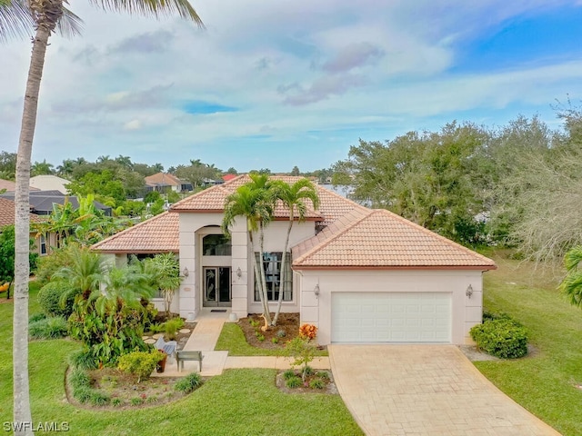 mediterranean / spanish house featuring a front lawn and a garage