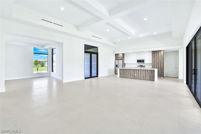 unfurnished living room featuring coffered ceiling, light tile floors, french doors, and beamed ceiling