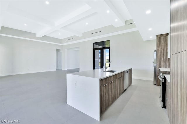 kitchen featuring beam ceiling, a center island with sink, stainless steel appliances, and sink