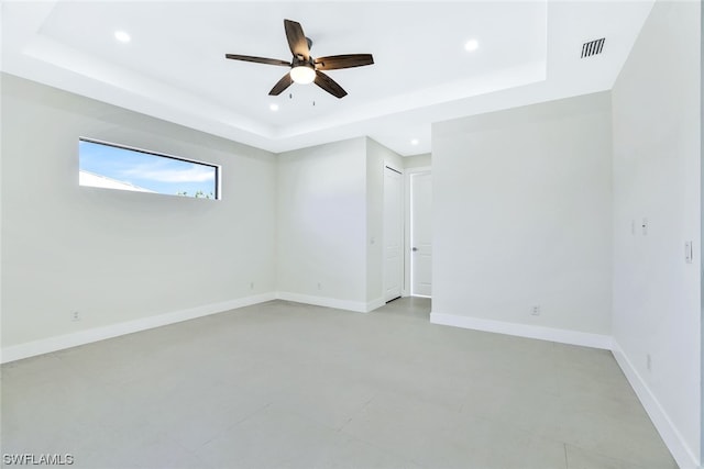 unfurnished room featuring ceiling fan, a raised ceiling, and light tile flooring