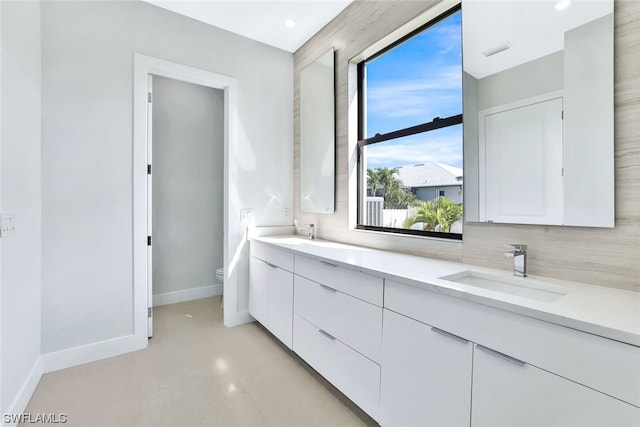 bathroom with dual vanity, backsplash, and toilet