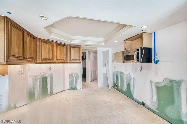 kitchen featuring a tray ceiling and light tile floors