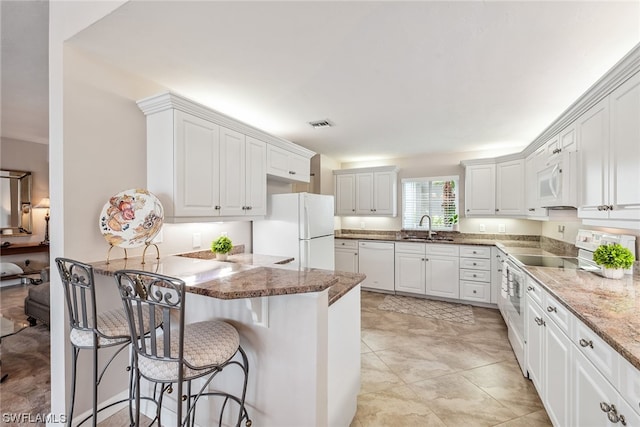 kitchen with white appliances, sink, light tile floors, and white cabinetry