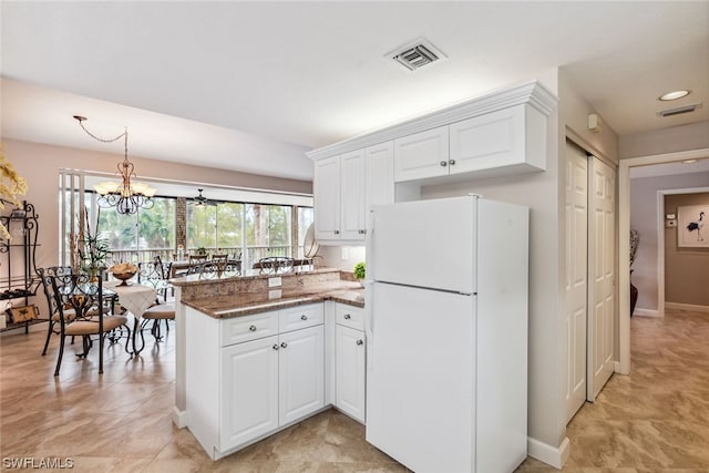 kitchen featuring white fridge, a notable chandelier, light tile floors, and white cabinets