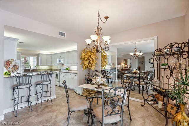 dining space with an inviting chandelier, sink, and light tile floors