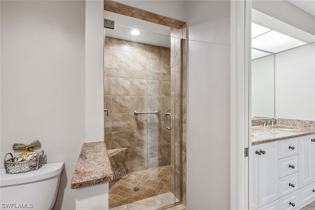 bathroom featuring large vanity, a shower with door, and toilet