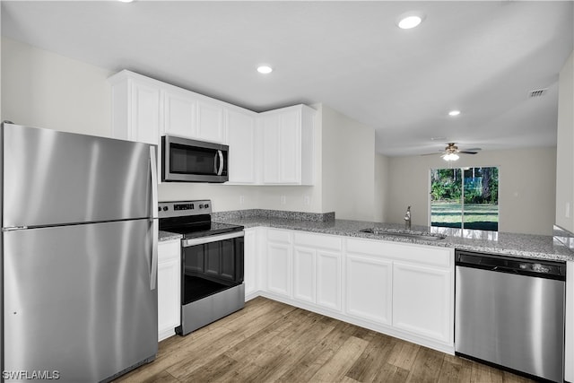 kitchen featuring white cabinetry, stainless steel appliances, ceiling fan, and light hardwood / wood-style flooring