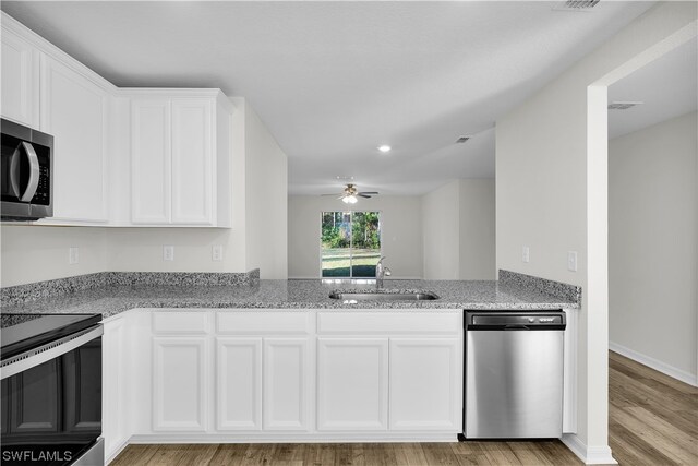 kitchen with stainless steel appliances, ceiling fan, white cabinetry, light wood-type flooring, and sink