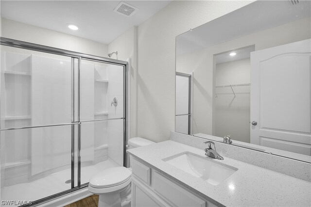 bathroom featuring toilet, a shower with door, hardwood / wood-style floors, and vanity