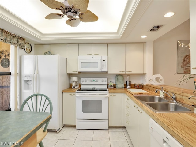 kitchen with a raised ceiling, sink, light tile patterned floors, and white appliances