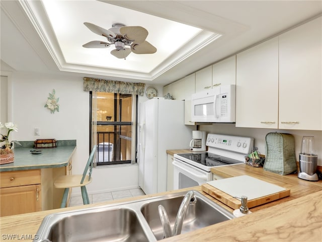 kitchen featuring sink, white cabinets, ceiling fan, a tray ceiling, and white appliances