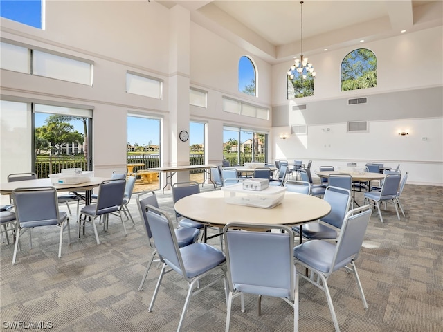 carpeted dining room with an inviting chandelier and a towering ceiling