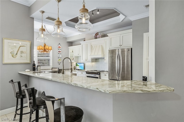 kitchen featuring white cabinets, appliances with stainless steel finishes, kitchen peninsula, and decorative light fixtures