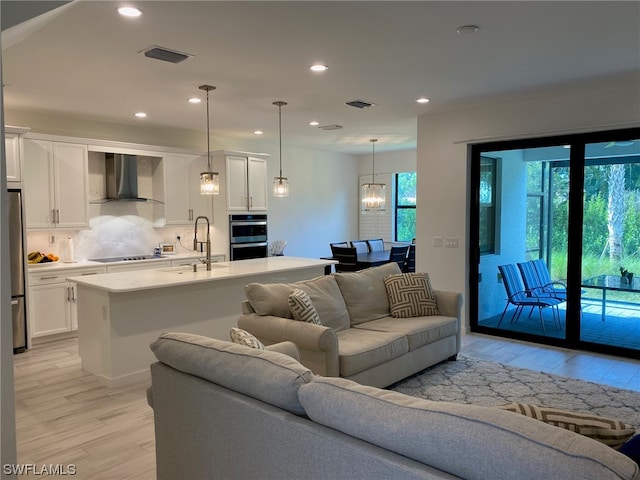 living room featuring sink, light hardwood / wood-style floors, and a notable chandelier