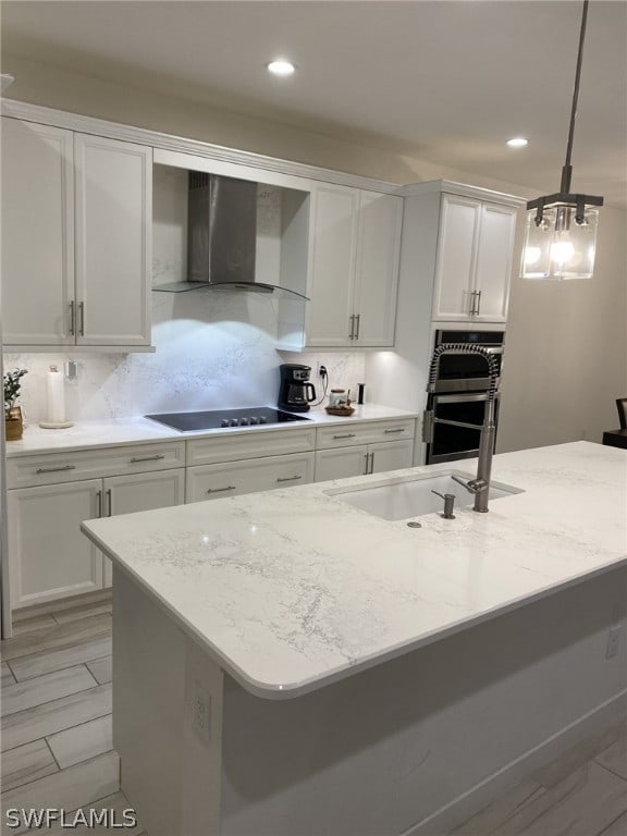 kitchen featuring pendant lighting, white cabinetry, backsplash, wall chimney range hood, and black electric cooktop