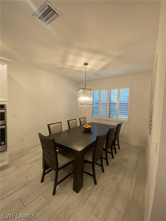 dining area with light hardwood / wood-style flooring and a notable chandelier