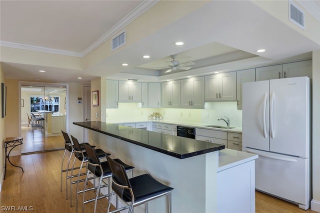 kitchen featuring ceiling fan, white fridge, light wood-type flooring, a kitchen bar, and a center island