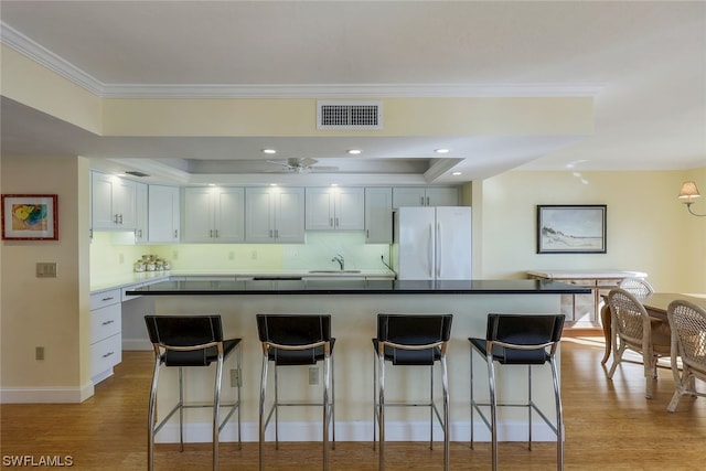 kitchen with a kitchen bar, tasteful backsplash, and white refrigerator