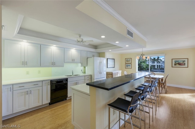 kitchen featuring light wood-type flooring, a tray ceiling, ceiling fan with notable chandelier, and white refrigerator