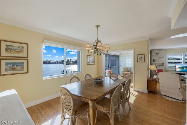 dining room with a chandelier, a water view, plenty of natural light, and light wood-type flooring