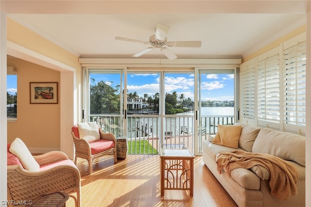 sunroom featuring ceiling fan, a healthy amount of sunlight, and a water view