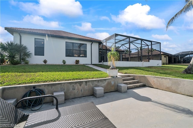 back of house with a yard, glass enclosure, and a patio