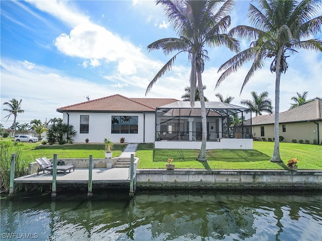 rear view of property featuring glass enclosure, a water view, and a lawn