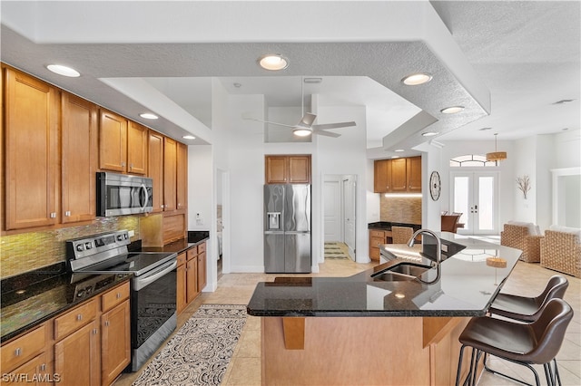 kitchen featuring light tile floors, a kitchen bar, appliances with stainless steel finishes, backsplash, and sink