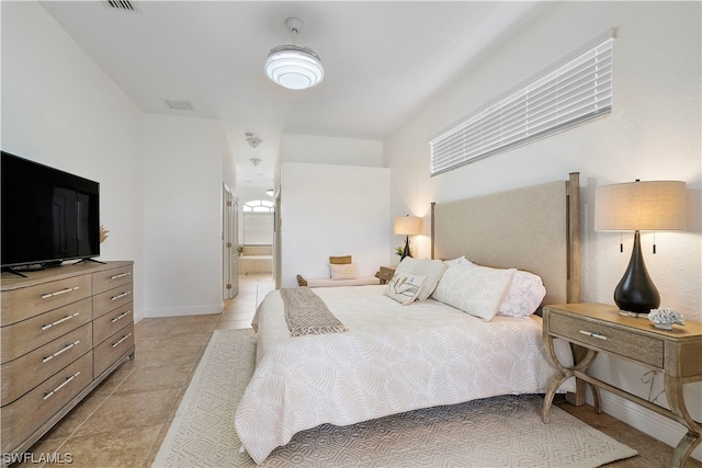 bedroom with light tile flooring, connected bathroom, and multiple windows